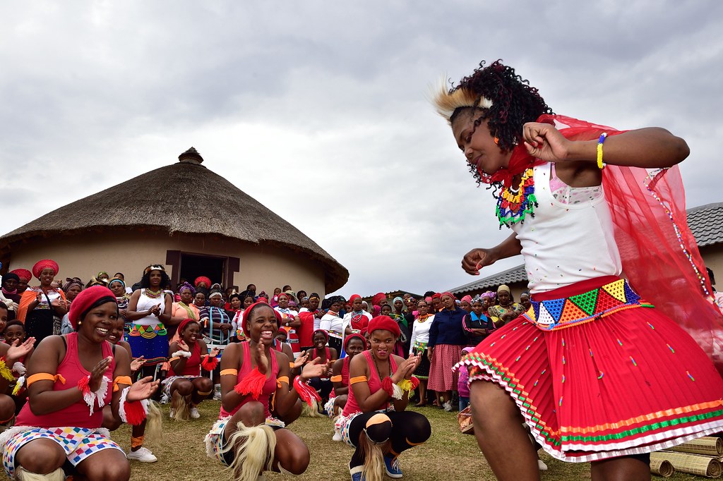 A large group of females dancing wearing traditional African clothing