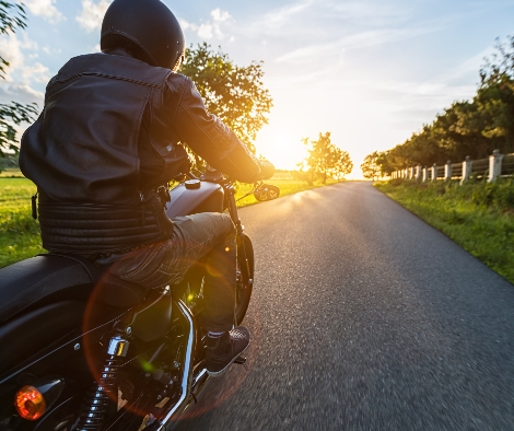 Somebody driving a motorbike with greenery on both sides of him