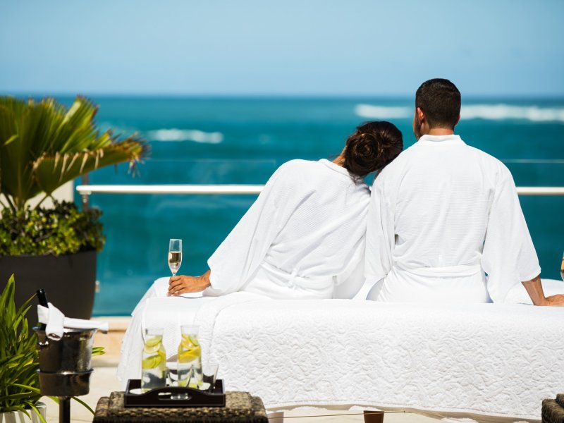 A couple sitting in robes and looking at the beach